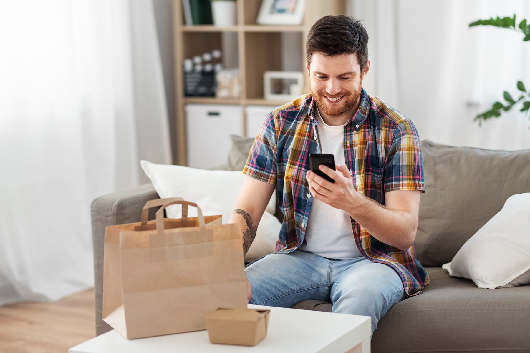 Guy looking at food ordering app after food is delivered