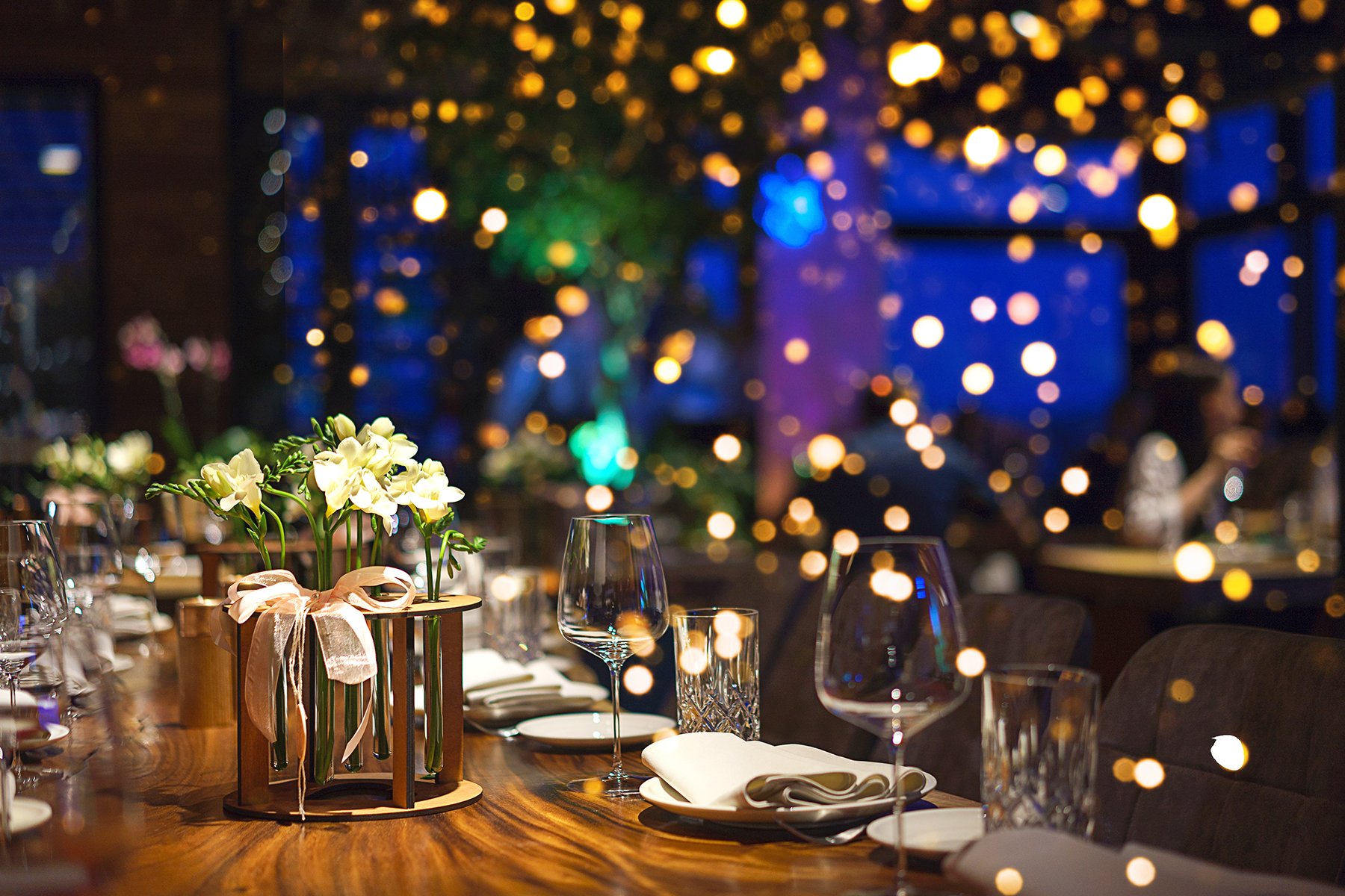 Holiday Dinner Table with Glassware and Warm Bokeh Lights in Background